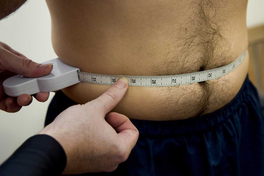 A fat man measuring waist